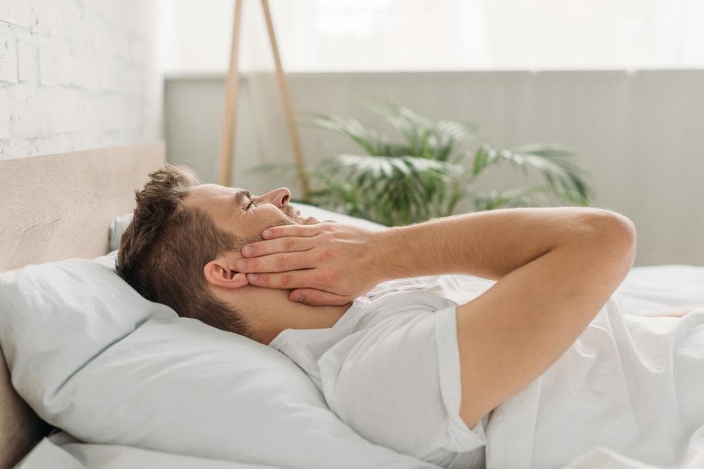 stock photo young man touching cheek while lying bed suffering toothache
