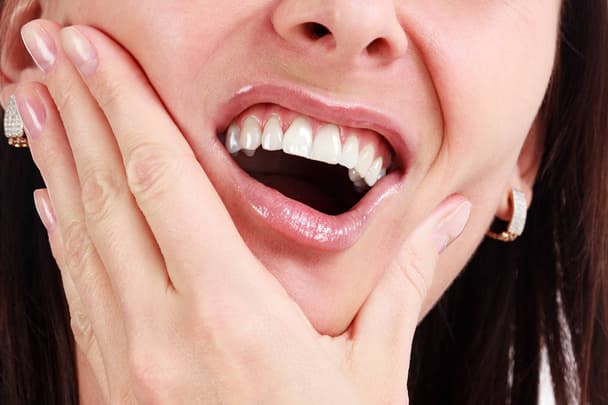 stock photo closeup of woman in strong toothache pain with hands over face