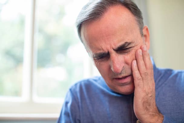 stock photo mature man suffering with toothache and rubbing painful tooth