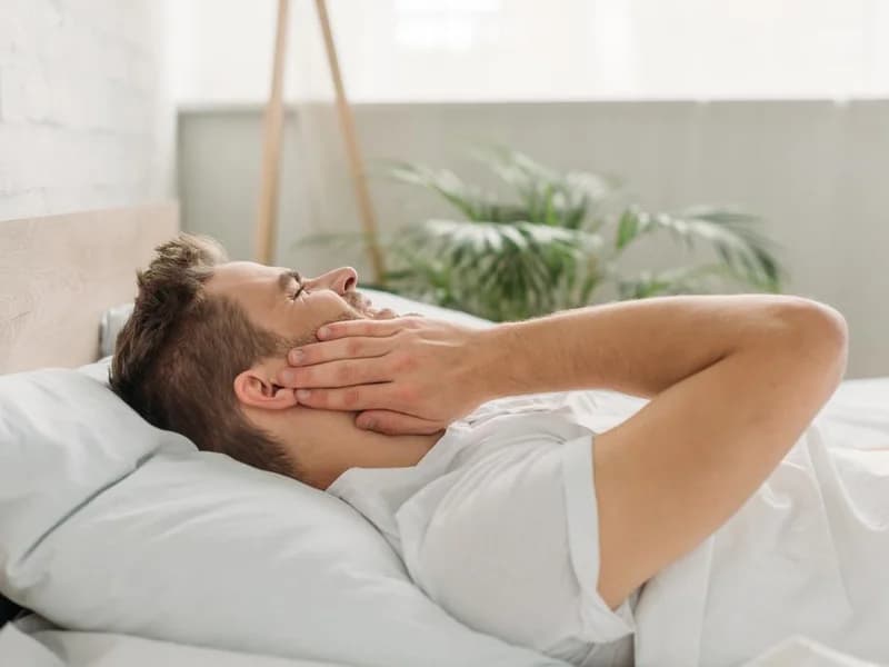 stock photo young man touching cheek while lying bed suffering toothache